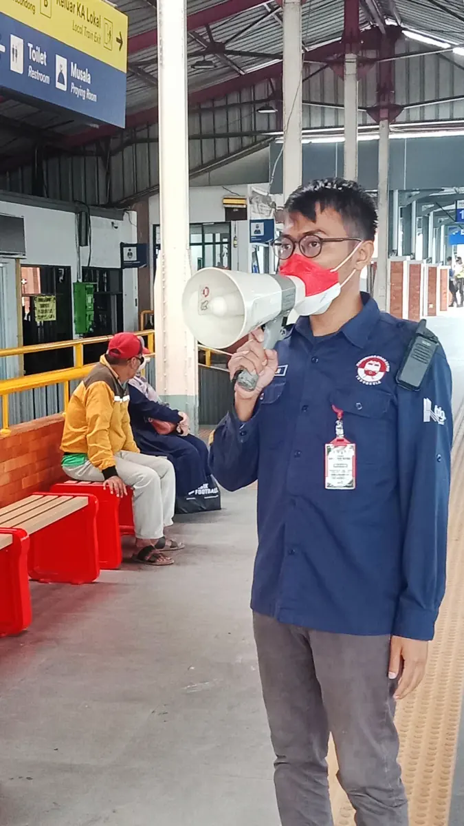 Dhiya memberi pengumuman dengan megafon di peron